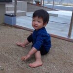 砂の上で座って笑顔の1歳児