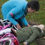 自転車で倒れた子供を介抱する女性