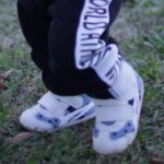 芝生の上で靴を履いて歩く1歳児の足