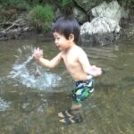 川の水を手ではじく1歳児