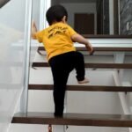室内の階段でガラスに手を着いて立って登る幼児