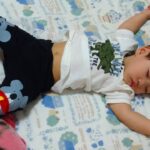 布団の上で大の字になって眠る1歳児
