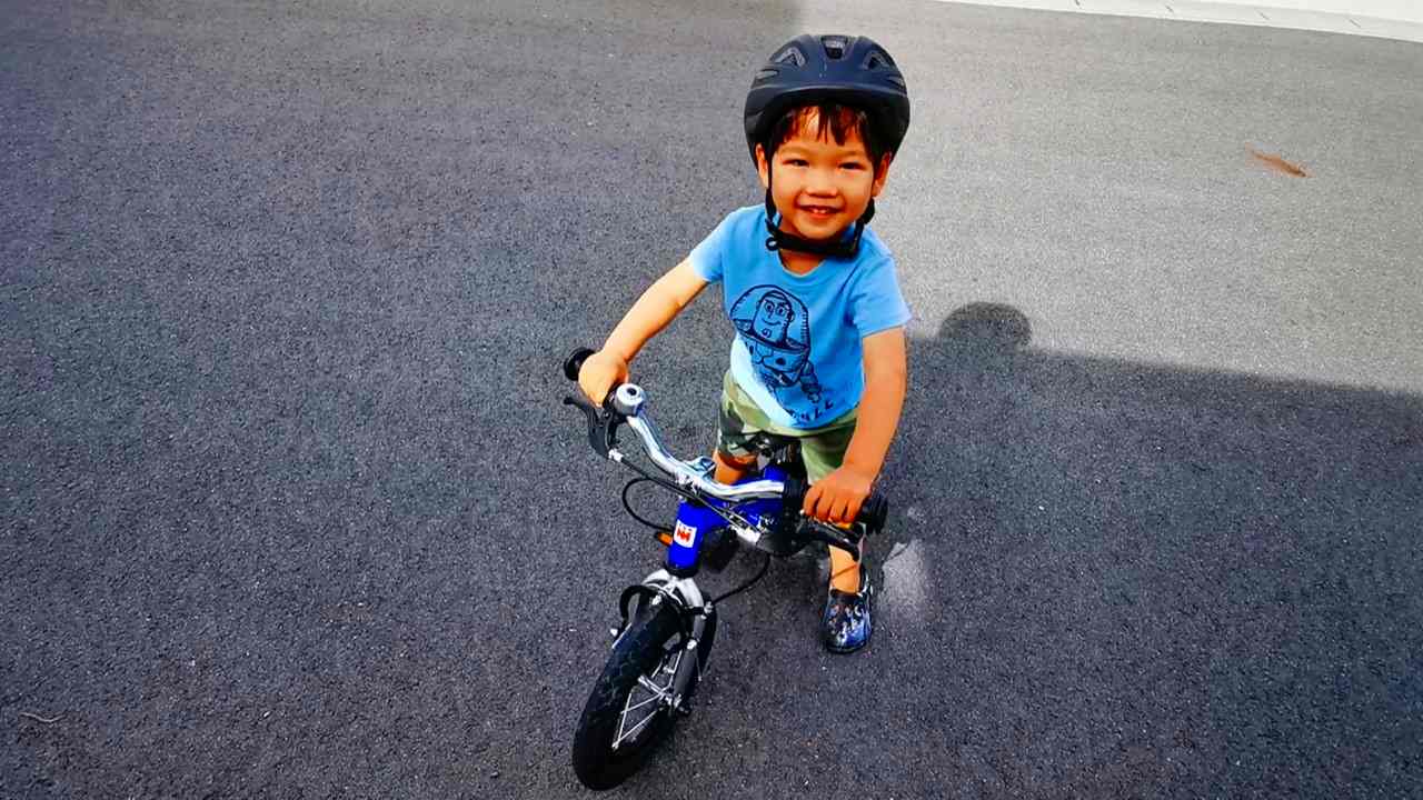 自転車にまたがって強い視線で見つめる2歳児
