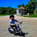 青空の下で笑顔で自転車に乗る2歳児