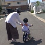 2歳児の自転車練習をフォローする女性