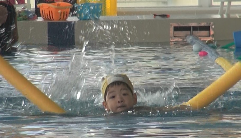 浮き輪を使って激しいバタ足で泳ぐ2歳児