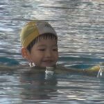 浮き輪を使って笑顔で泳ぐ子供
