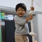 吊られたロープを握って笑顔を見せる子供