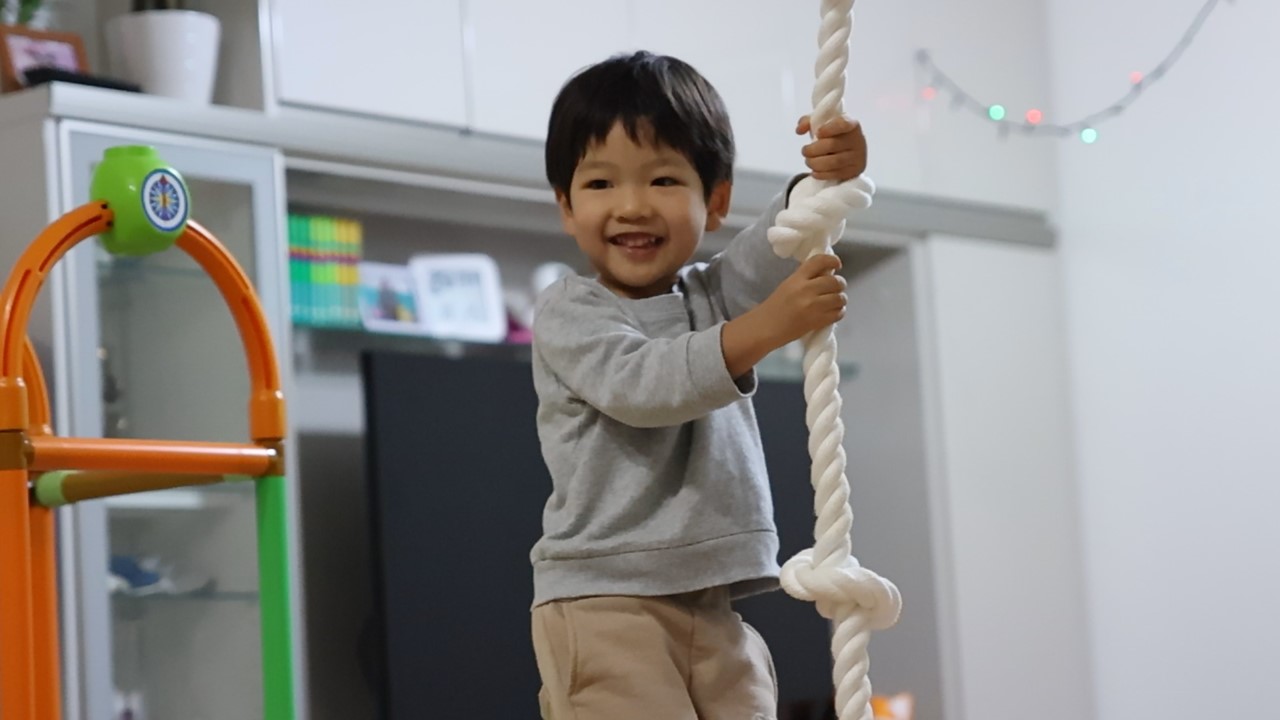 吊られたロープを握って笑顔を見せる子供